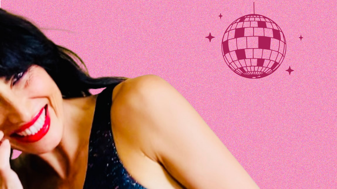 Brunette model wearing black shiny one shoulder crop, pink background